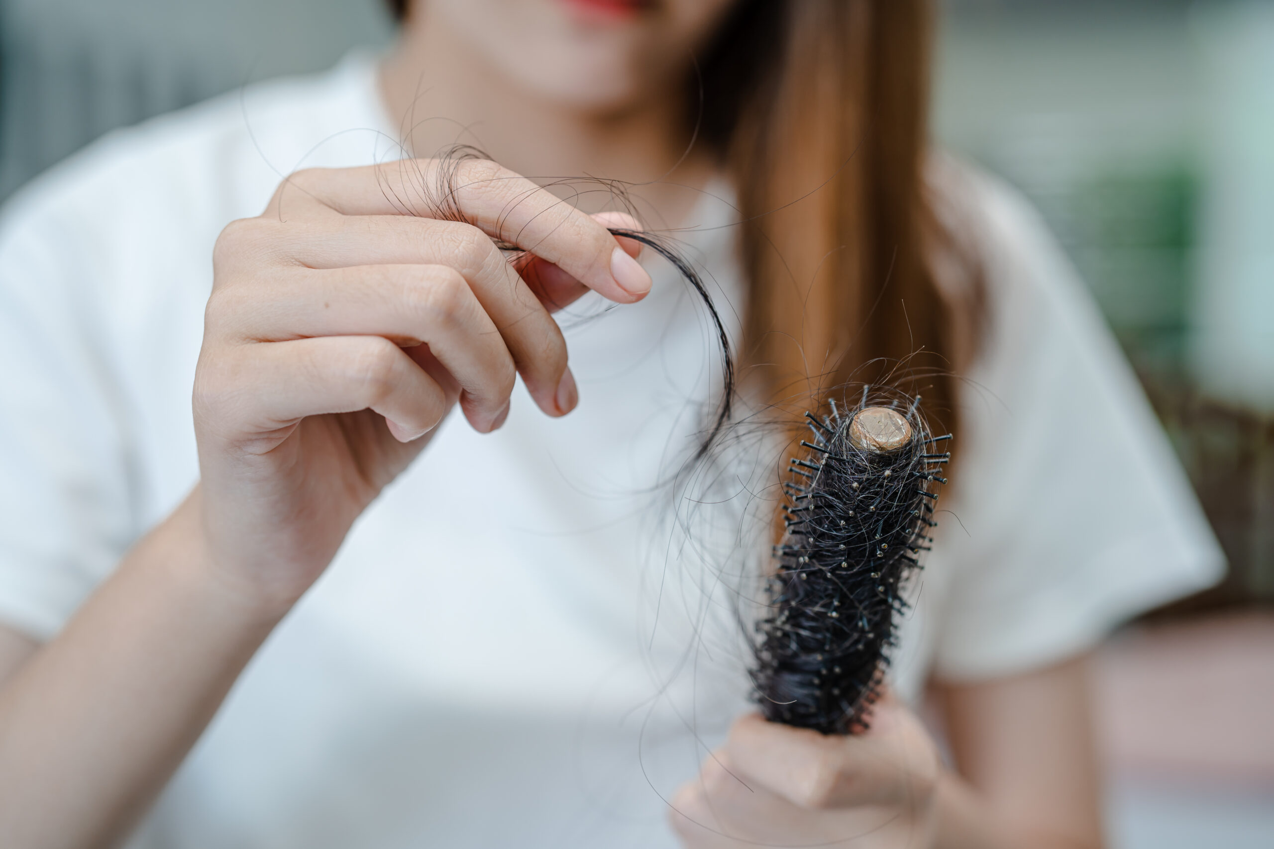 mulher com pente na mão com queda de cabelo